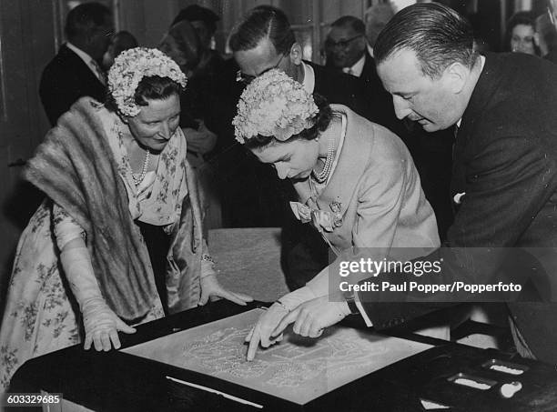 Queen Elizabeth II of Great Britain and Queen Juliana of the Netherlands view a large reproduction of the Royal Cypher set in diamonds, with director...