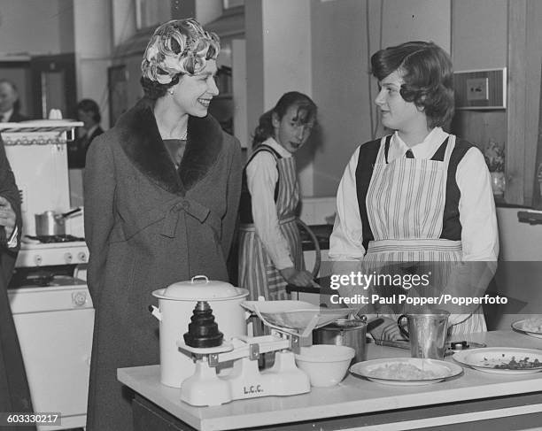 Queen Elizabeth II talks to 13 year old Carol Hummesston in the cooking classroom during a visit to St Michael's School in Westminster, London on...