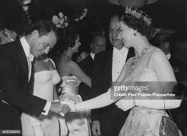 Queen Elizabeth II shakes hands with American singer and actor, Frank Sinatra as she meets the stars attending the premiere of the Danny Kaye film...