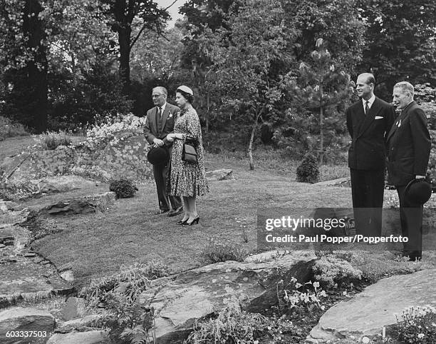 Queen Elizabeth II talks with an unknown man as the Duke of Edinburgh talks to the Hon David Bowes-Lyon during a viewing of a rock garden at the...