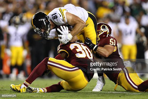 Tight end Jesse James of the Pittsburgh Steelers is tackled by defensive back David Bruton and inside linebacker Will Compton of the Washington...