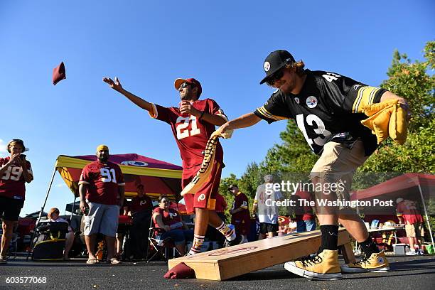 Ankit Mittal, of Ellicott City, Md., tosses a bean bag as his friend Shean Flynn, of Newport News, Va., waves his Terrible Towel as the two were...