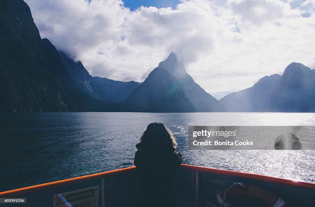 Child on a boat, taking a photo of Mitre Peak, in Milford Sound