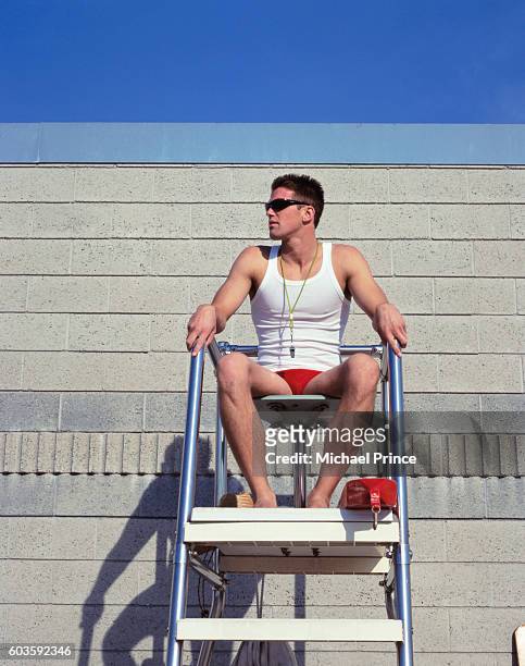 man sitting at lifeguard station - rettungsschwimmer stock-fotos und bilder