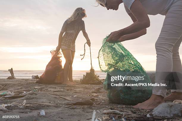 mother and daughter collect garbage from beach - clean ocean stock pictures, royalty-free photos & images