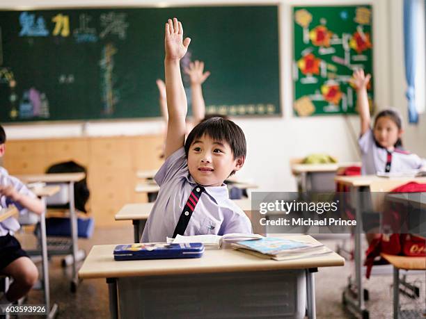 students in classroom raising hands - 手を挙げる ストックフォトと画像