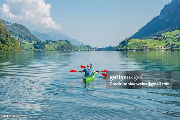 a couple paddling on lungernsee lake lungern in switzerland between the mountains alps landscape on a summer day - lungern switzerland stock-fotos und bilder