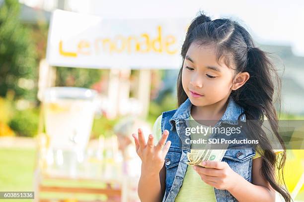 young girl counts money made from lemonade stand - earnings season stock pictures, royalty-free photos & images