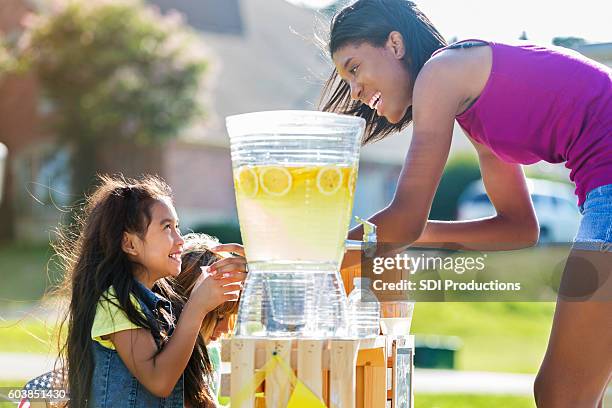 happy girls sell lemonade to adult customer - traditional lemonade stock pictures, royalty-free photos & images