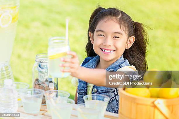 un petit entrepreneur excité remet à son client un verre de limonade maison - buvette photos et images de collection