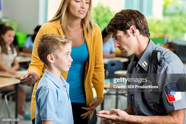 serious security officer talks with elementary student at school - charter school stock pictures, royalty-free photos & images