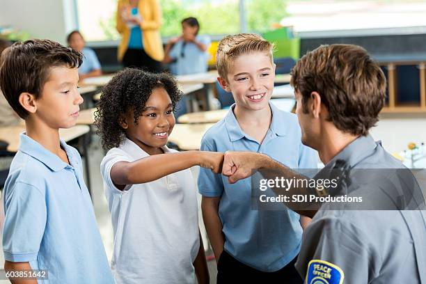 african american student gives policeman a fist bump at school - friendly police stock pictures, royalty-free photos & images