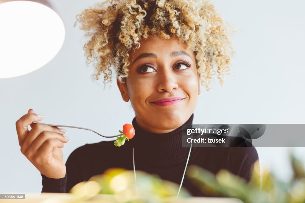 Cheveux bouclés jeune femme mangeant de la salade
