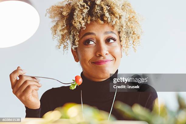 curly hair young woman eating salad - woman eating fork stock pictures, royalty-free photos & images