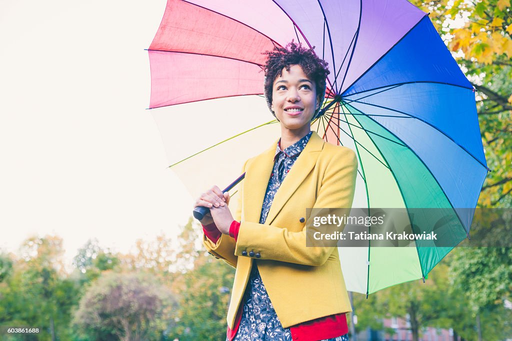 Woman under colorful umbrella in a park (London, UK)