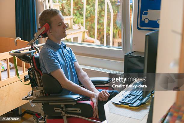 young disabled man playing computer game - spinal cord injury stock pictures, royalty-free photos & images