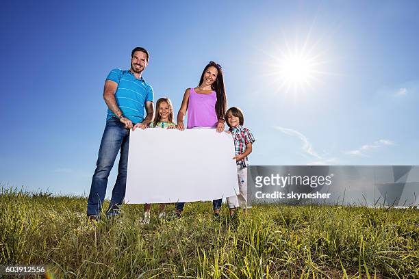 below view of happy family holding blank placard in nature. - couple placard stock pictures, royalty-free photos & images