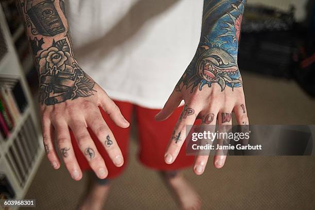 close up of a mid 20's tattoo enthusiasts hands - multi coloured shirt stock pictures, royalty-free photos & images