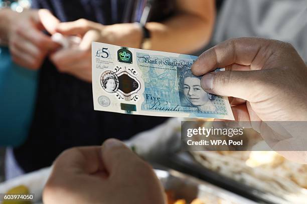 Food seller holds a new polymer five pound note at Whitecross Street Market on September 13, 2016 in London, United Kingdom. The new plastic note is...