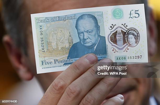 Bank of England governor Mark Carney poses with a new polymer five pound note at Whitecross Street Market on September 13, 2016 in London, United...