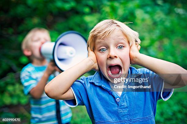 kleiner junge wird von seinem bruder angebrüllt - covering ears stock-fotos und bilder