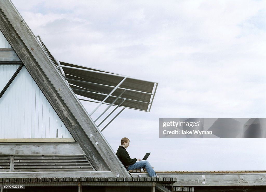 Man on Roof Using Laptop