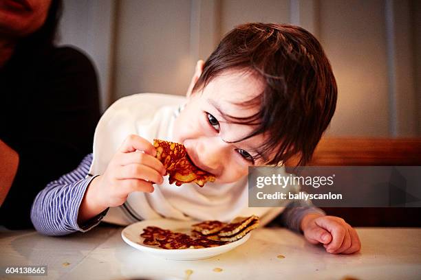 boy eating pancakes at table - pancake day foto e immagini stock