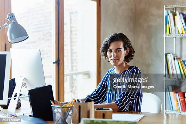 creative businesswoman sitting at desk in office - business woman sitting imagens e fotografias de stock
