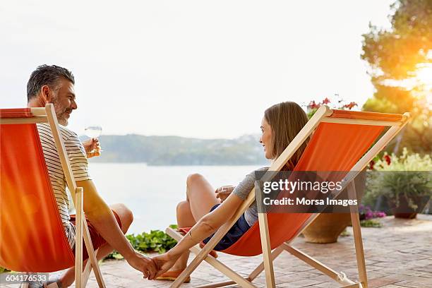 mature couple holding hands while enjoying wine - holiday romance stock pictures, royalty-free photos & images