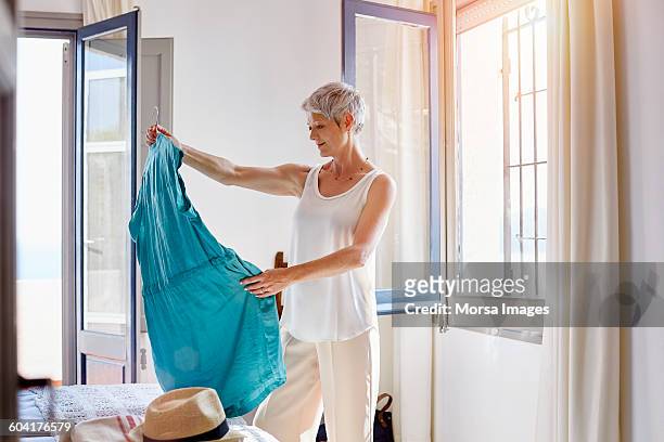 thoughtful senior woman looking at dress - vestito da donna foto e immagini stock