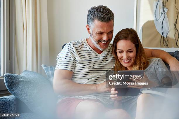 happy couple using digital tablet at home - couple couch imagens e fotografias de stock