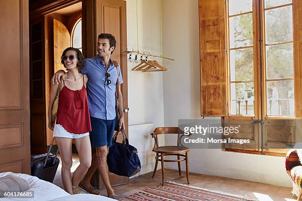 happy couple with luggage entering in hotel room - hotel stock pictures, royalty-free photos & images