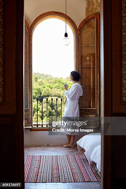 woman having coffee while looking through window - 33 arches stock pictures, royalty-free photos & images