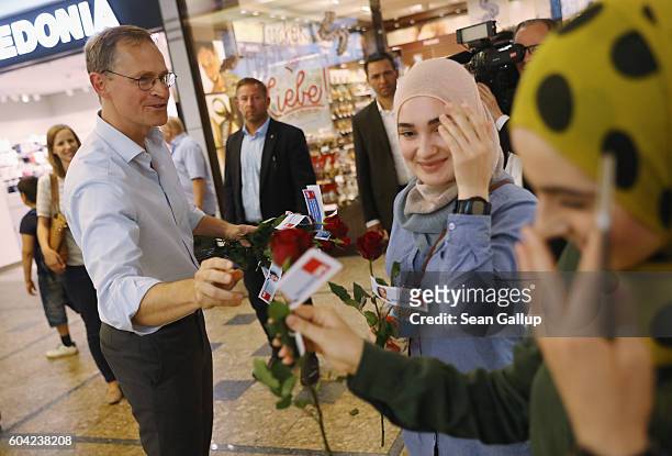 German Social Democrat and current Berlin Mayor Michael Mueller distributes roses to young Muslim women as he campaigns in Berlin state elections at...