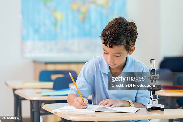 schoolboy concentrates while working on assignment - schoolboy stock pictures, royalty-free photos & images
