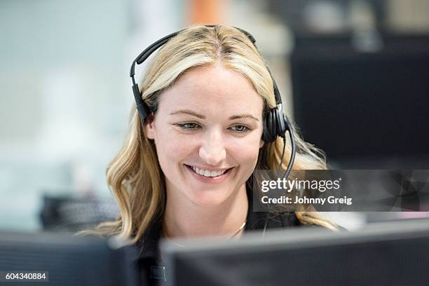 woman in office wearing telephone headset, looking down - call centre stock pictures, royalty-free photos & images