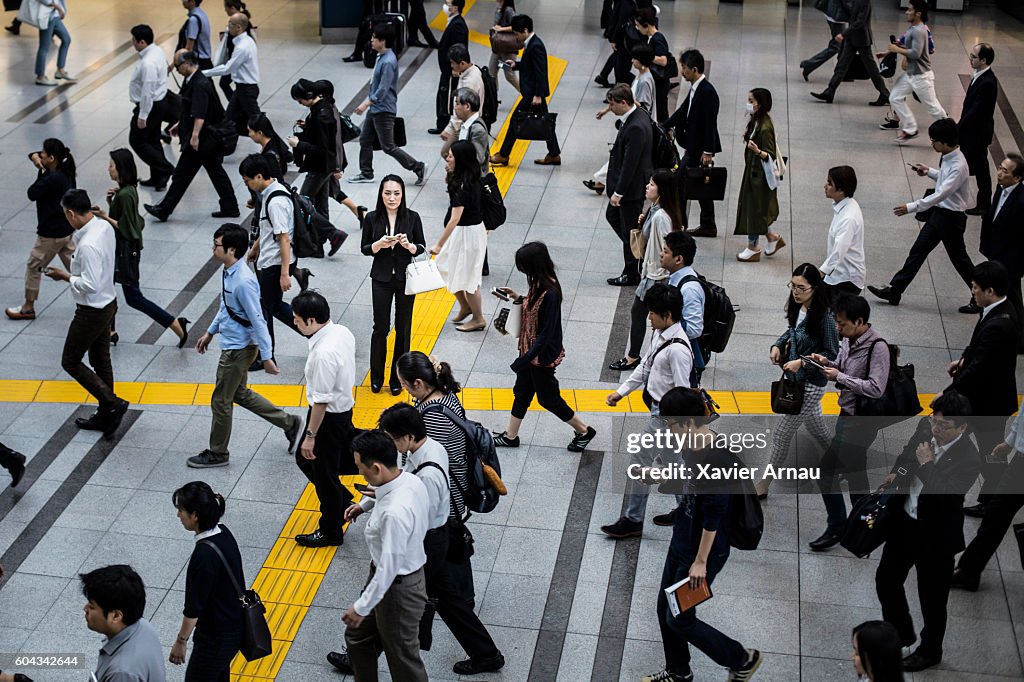 Japanische Frau reden auf der Mobiltelefon umgeben von Pendlern