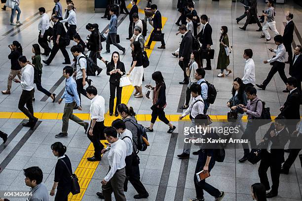 japanese woman talking on the mobile phone surrounded by commuters - human rights business stock pictures, royalty-free photos & images