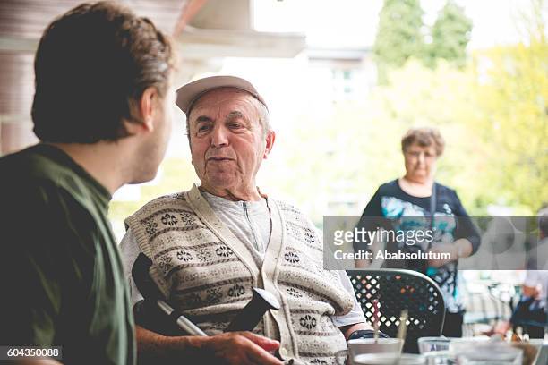 happy senior man in wheelchair and grandson having coffee, europe - grandma cane bildbanksfoton och bilder