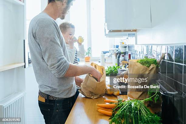 father and son organizing groceries in the kitchen - young man groceries kitchen stockfoto's en -beelden