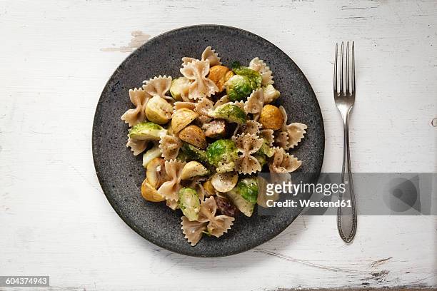 dish of brussels sprouts with sweet chestnuts and whole-grain noodles - bow tie pasta stock pictures, royalty-free photos & images
