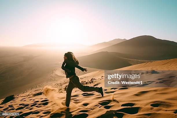 namibia, namib desert, sossusvlei, woman running down the dune 45 at sunrise - namibia women stock pictures, royalty-free photos & images