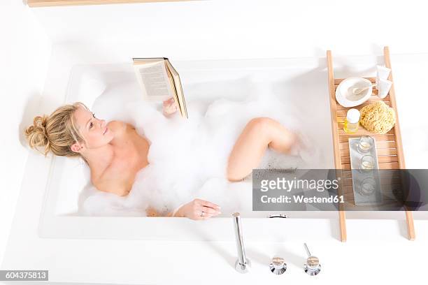 woman reading book in bubble bath - schaumbad stock-fotos und bilder