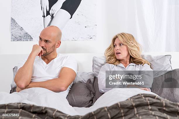 mature couple lying in bed, having relationship problems - bed conflict stock pictures, royalty-free photos & images