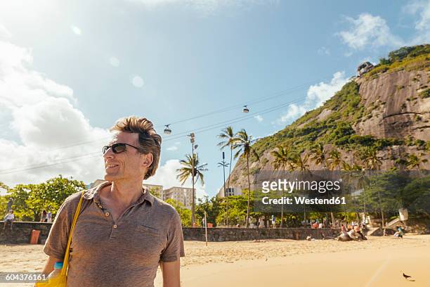 brazil, morro da urca behind a male tourist on praia vermelha in rio de janeiro - confidence male landscape stock-fotos und bilder