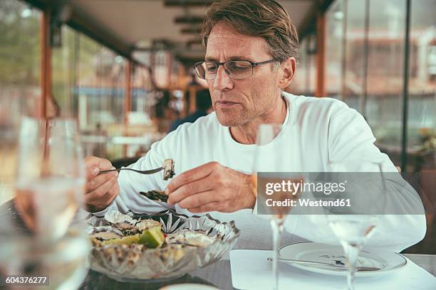 brazil, florianopolis, man eating fresh oysters in a restaurant - mussels stock pictures, royalty-free photos & images