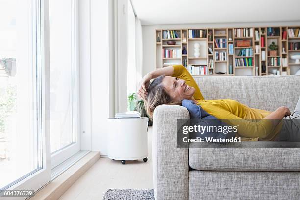 happy woman at home lying on couch - homme relax stock-fotos und bilder