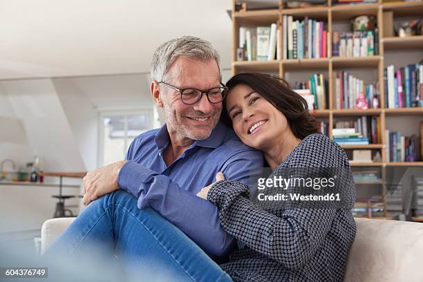 smiling mature couple cuddling at home - 55 59 años fotografías e imágenes de stock