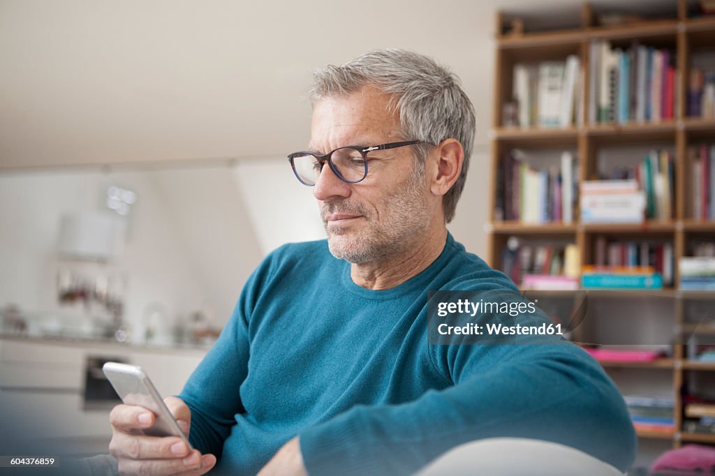 Mature man at home looking at cell phone