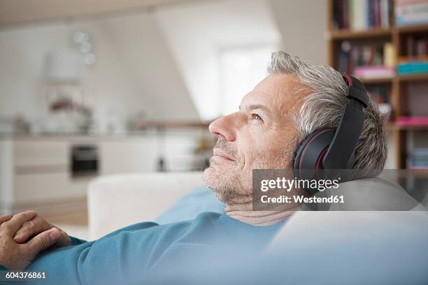 relaxed man at home wearing headphones listening to music - music at home stock-fotos und bilder